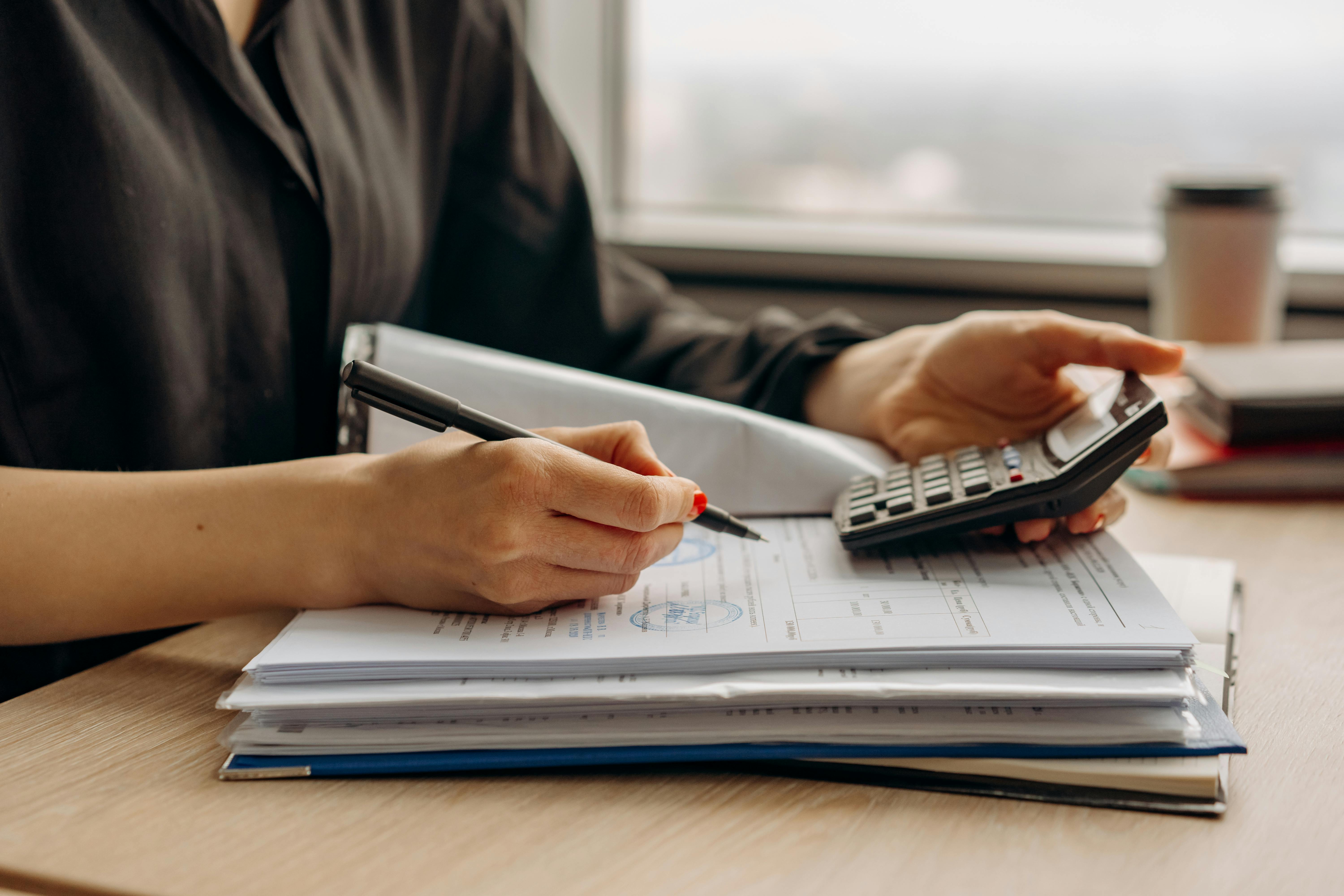 Image of a person holding a calculator while reviewing financial documents.